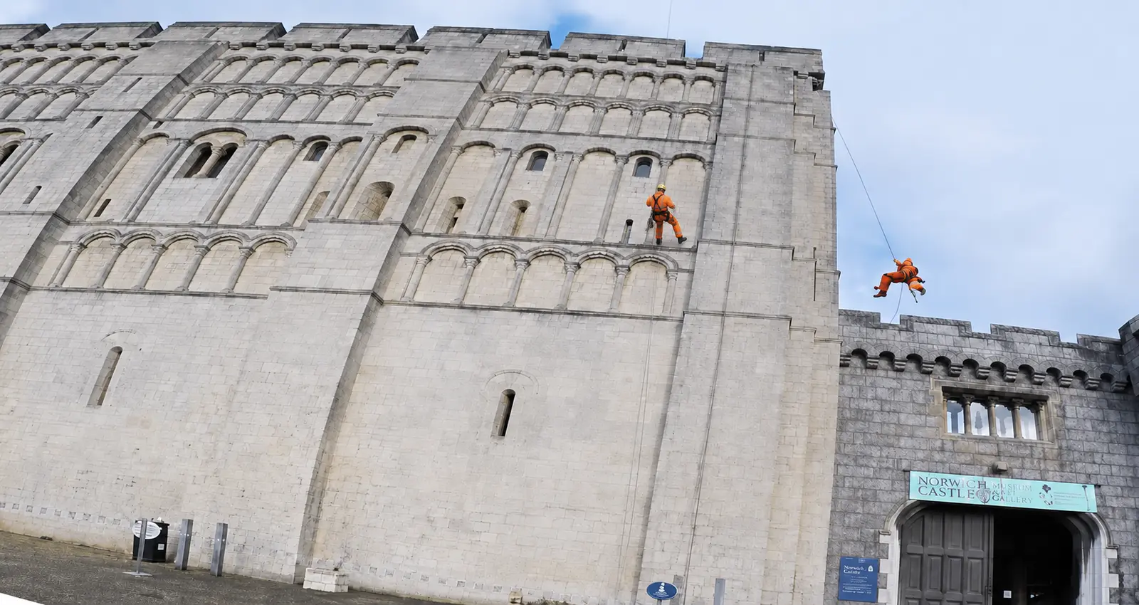 Enhanced Norwich Castle visual showing two rope-access technicians in orange overalls