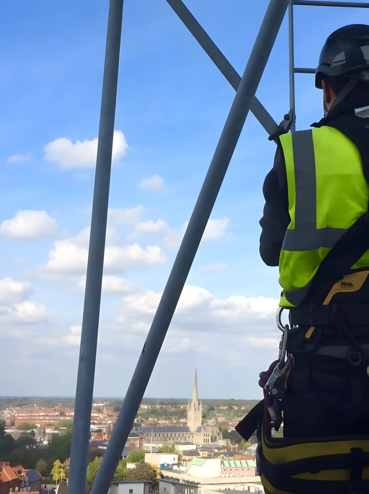 Rope-access technician at height with Norwich Cathedral visible across the city