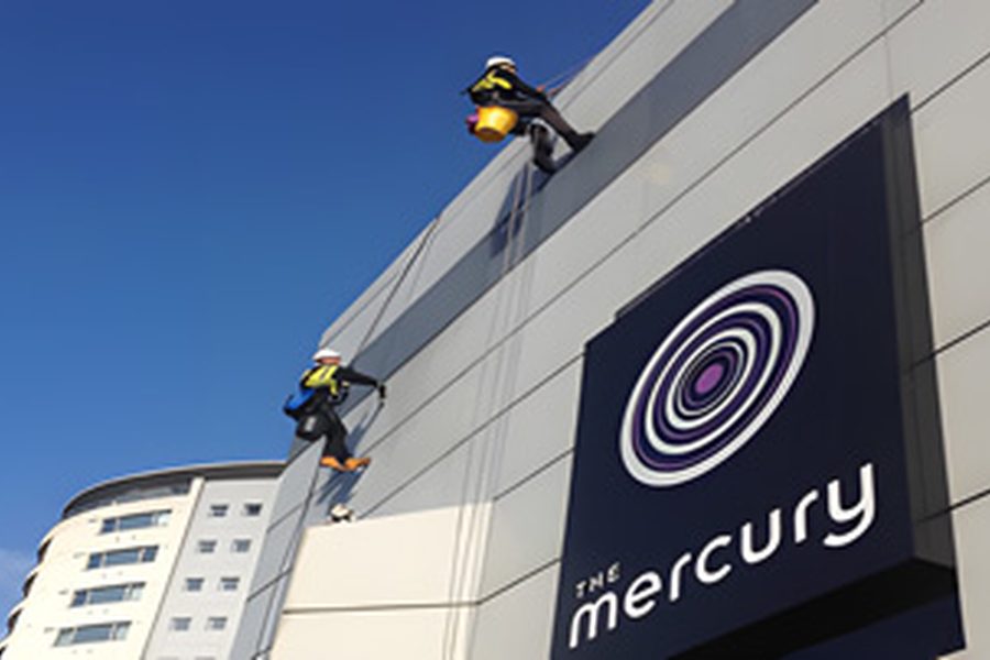 Rope-access technicians cleaning a commercial building exterior