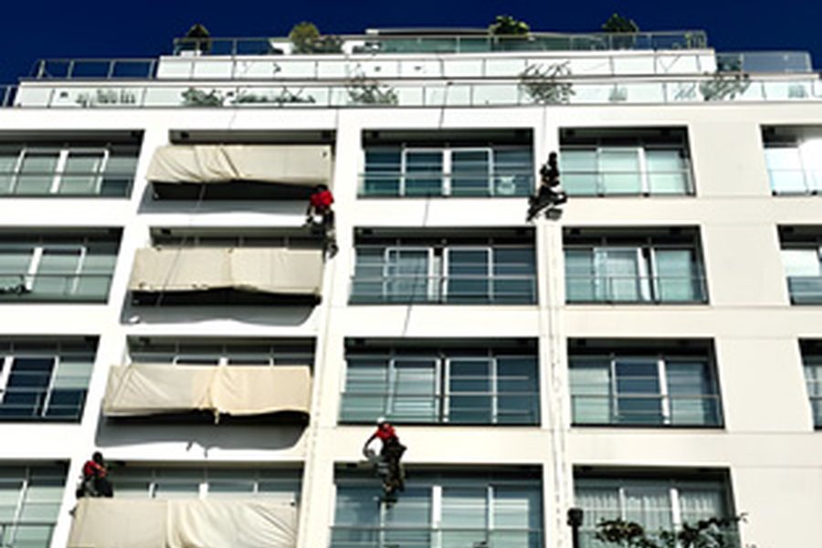 Rope access painting and coating work across a commercial elevation