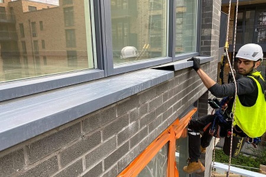 Technician repairing sealant around high-level windows