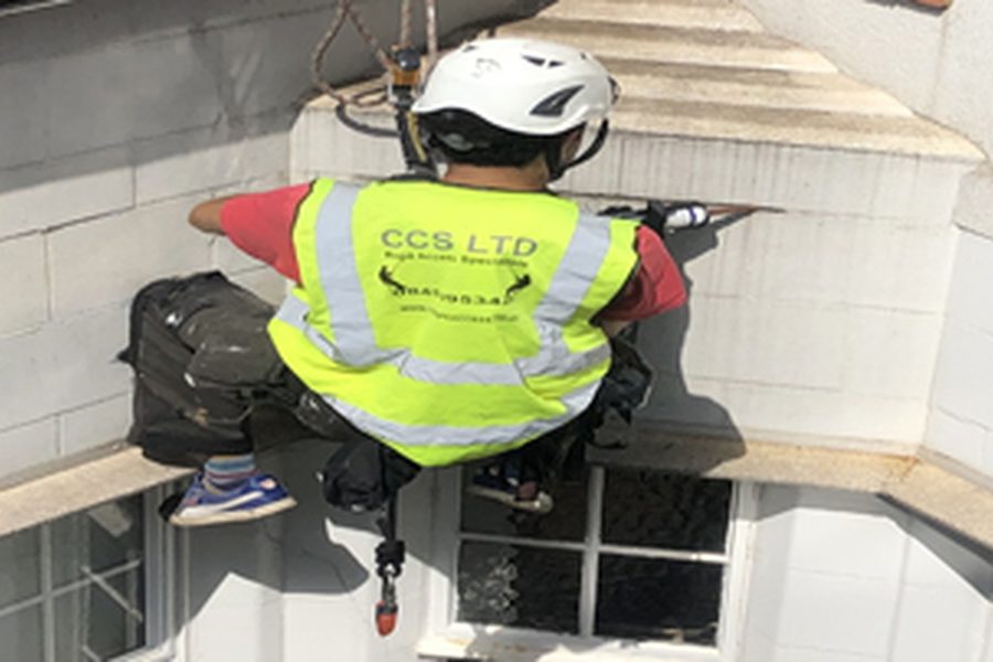 Rope access technician installing a sign at height