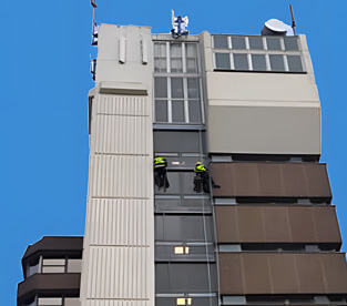 A skilled rope access technician performing building maintenance and brickwork repairs on a high-rise building.