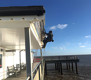 Proficient abseilers performing roof repairs using rope access techniques, showcasing their ability to efficiently address roofing issues with precision and care.